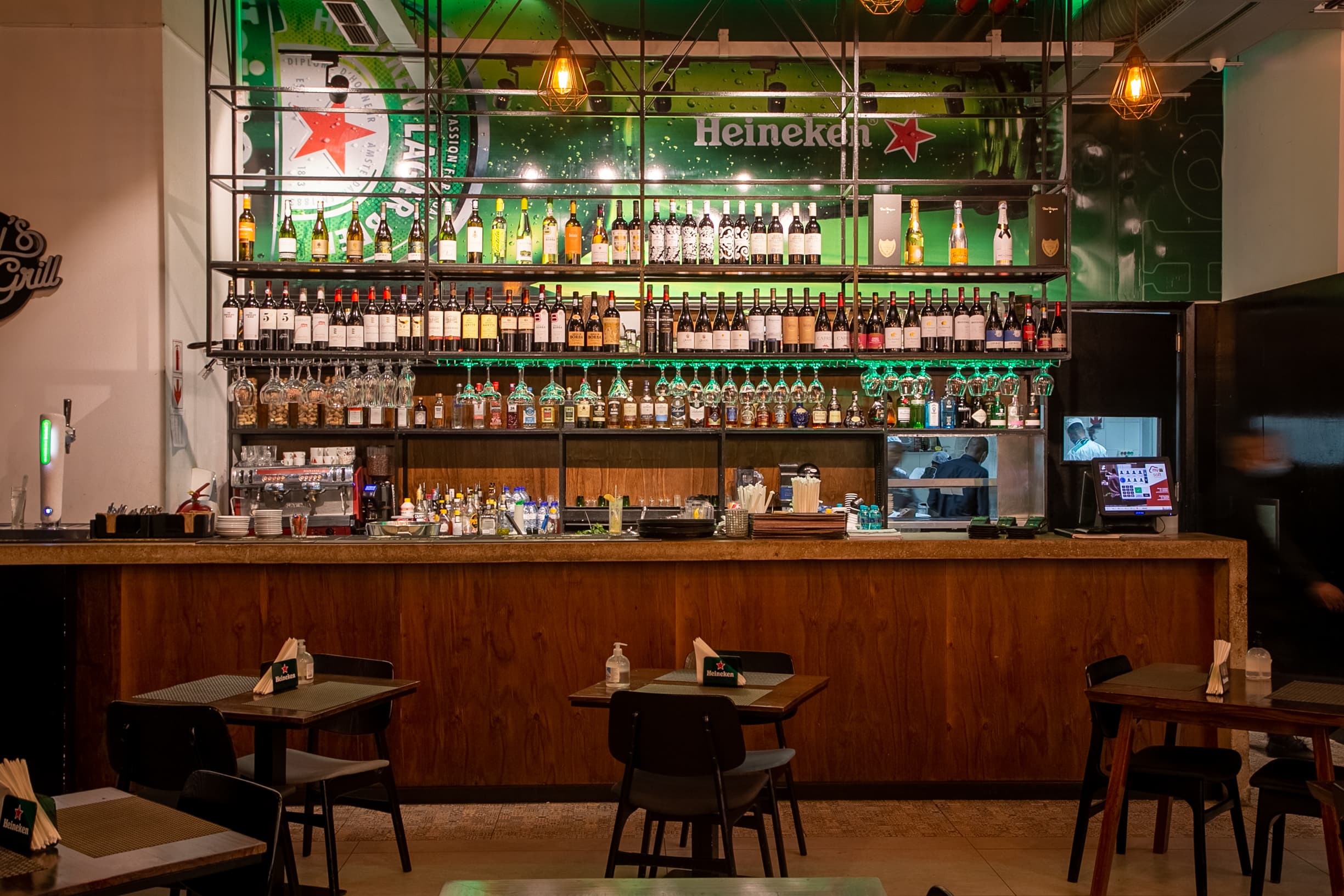 Bar do Jimmy’s com prateleiras de garrafas e néon verde