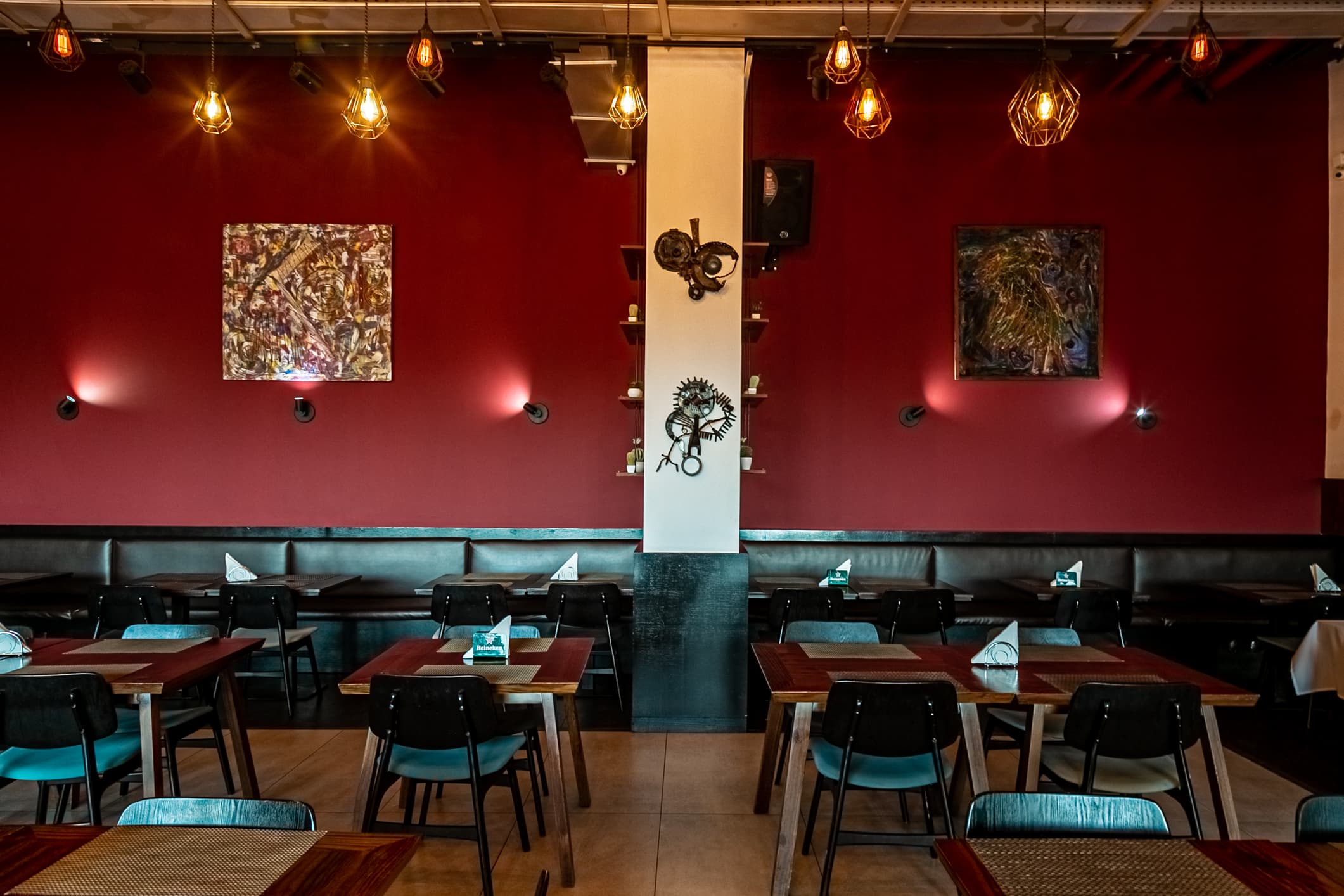 Sala interior do Jimmy’s com parede vermelha, arte e lâmpadas industriais